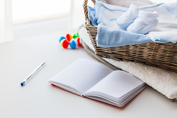 Image showing close up of baby clothes for newborn and notebook