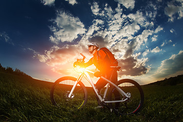 Image showing biker in orange jersey riding on green summer field