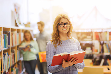 Image showing happy student girl or woman with book in library