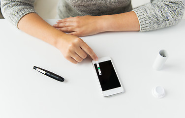Image showing close up of woman with smartphone doing blood test