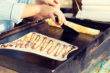 Image showing close up of cook frying pancakes at street market