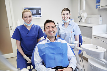 Image showing happy female dentists with man patient at clinic