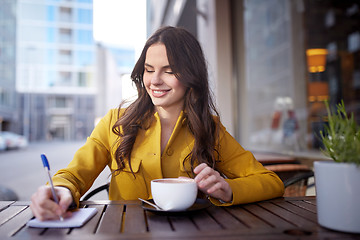 Image showing happy woman with notebook drinking cocoa at cafe