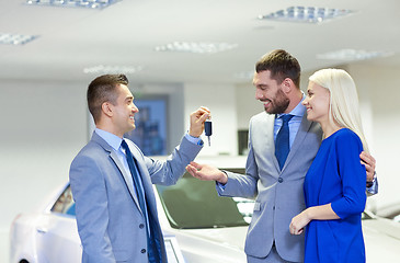 Image showing happy couple with car dealer in auto show or salon