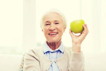 Image showing happy senior woman with green apple at home