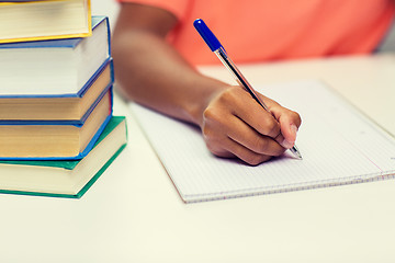 Image showing close up of african woman hand writing to notebook