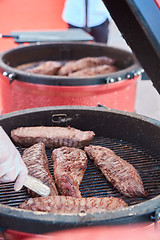 Image showing thick strip steak being grilled outdoors. Shallow dof