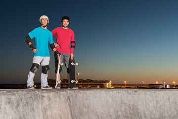 Image showing Two skateboarders standing near a concrete pool 