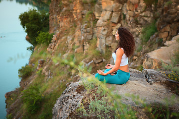 Image showing Young woman is practicing yoga near river