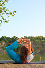 Image showing Young woman is practicing yoga near river