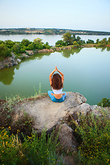 Image showing Young woman is practicing yoga near river