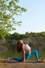 Image showing Young woman is practicing yoga near river