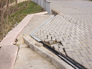 Image showing The destruction of the pedestrian walkway of pavers fixed concrete screed, as well as the breaking behavior of the fence