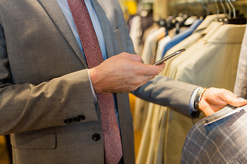 Image showing close up of man with smartphone at clothing store