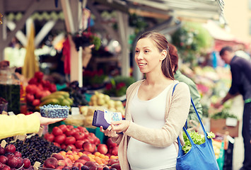 Image showing pregnant woman with wallet buying food at market