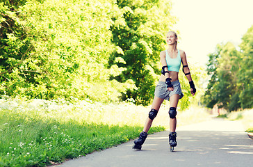 Image showing happy young woman in rollerblades riding outdoors