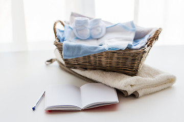 Image showing close up of baby clothes for newborn and notebook