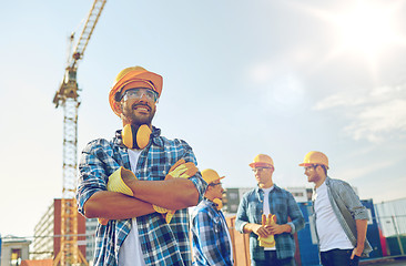 Image showing group of smiling builders in hardhats outdoors