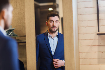 Image showing man trying jacket on at mirror in clothing store