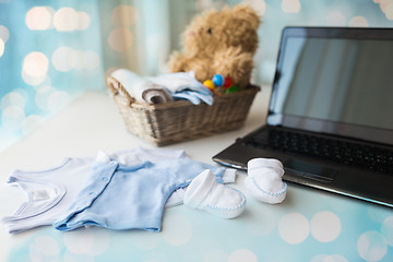 Image showing close up of baby clothes, toys and laptop at home