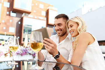 Image showing happy couple with tablet pc at restaurant terrace