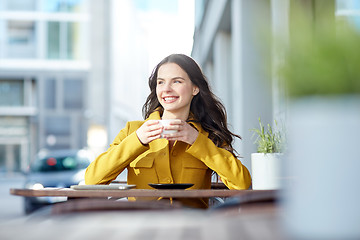 Image showing happy woman drinking cocoa at city street cafe