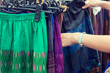 Image showing close up of hands choosing skirts at street market