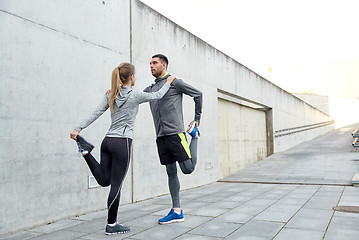 Image showing couple of sportsmen stretching leg on city street