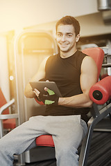 Image showing smiling young man with tablet pc computer in gym