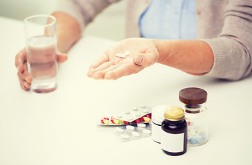 Image showing close up of senior woman with pills and water 