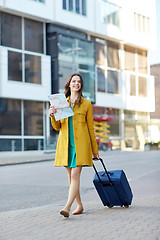 Image showing happy young woman with travel bag and map in city
