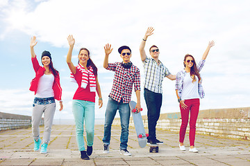Image showing group of smiling teenagers waving hands