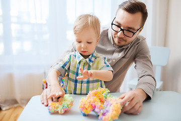 Image showing father and son playing with ball clay at home