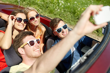 Image showing friends driving in cabriolet car and taking selfie