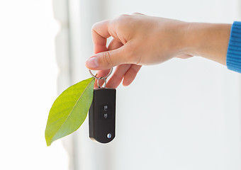 Image showing close up of hand holding car key with green leaf