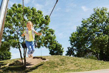 Image showing happy little girl swinging on swing at playground