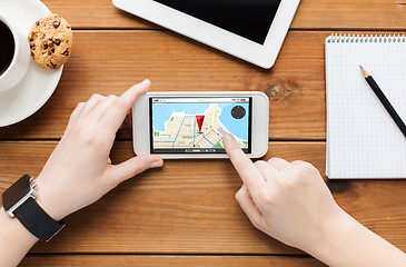 Image showing close up of woman with smartphone on wooden table