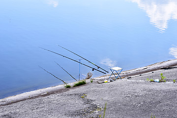 Image showing Chair with fishing poles and fishing equipment at the lake