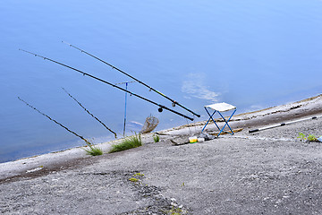 Image showing Chair with fishing poles and fishing equipment at the lake