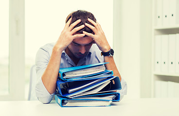 Image showing sad businessman with stack of folders at office