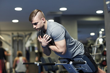 Image showing young man flexing back muscles on bench in gym