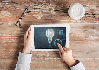 Image showing close up of hands with tablet pc and lighting bulb