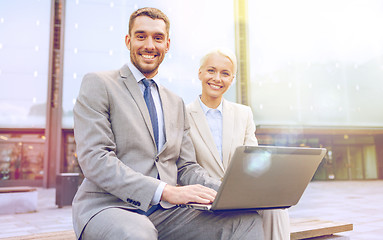 Image showing smiling businesspeople with laptop outdoors