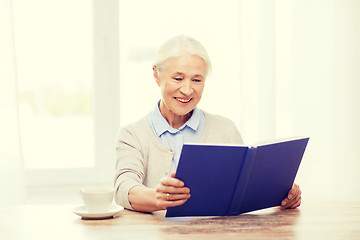 Image showing happy smiling senior woman reading book at home