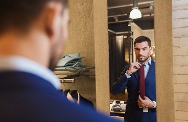 Image showing man trying tie on at mirror in clothing store