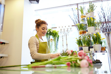 Image showing smiling florist woman making bunch at flower shop