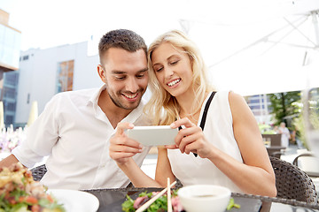 Image showing happy couple with smatphone at restaurant terrace