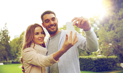 Image showing happy couple with smartphone taking selfie in park