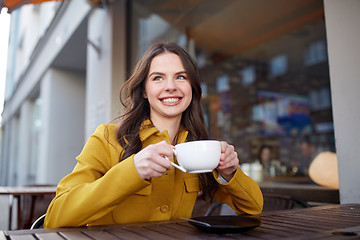 Image showing happy woman drinking cocoa at city street cafe