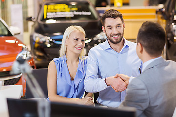 Image showing happy couple with car dealer in auto show or salon